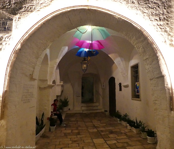 Torbogen bei Hof am Abend mit Regenschirm-Lampen